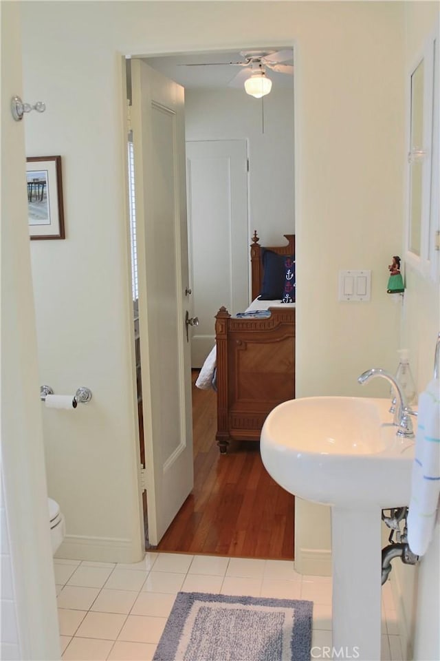 ensuite bathroom featuring a ceiling fan, wood finished floors, toilet, and baseboards