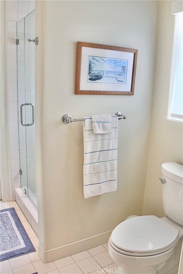 bathroom featuring toilet, a shower stall, tile patterned floors, and baseboards