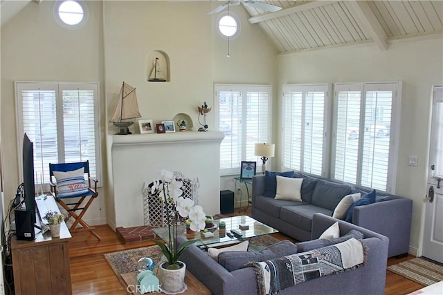 living area with ceiling fan, wood finished floors, high vaulted ceiling, and beamed ceiling