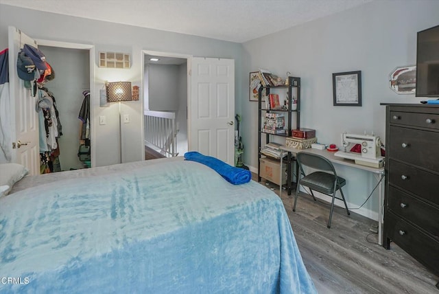 bedroom with wood finished floors, baseboards, a closet, and a walk in closet