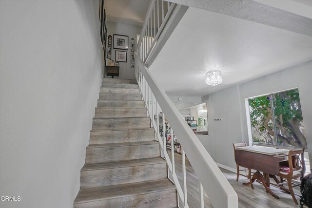stairway with wood finished floors and a chandelier