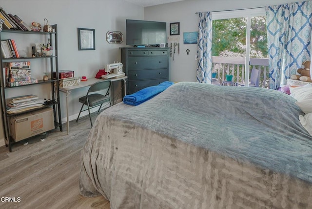 bedroom featuring wood finished floors, access to outside, and baseboards