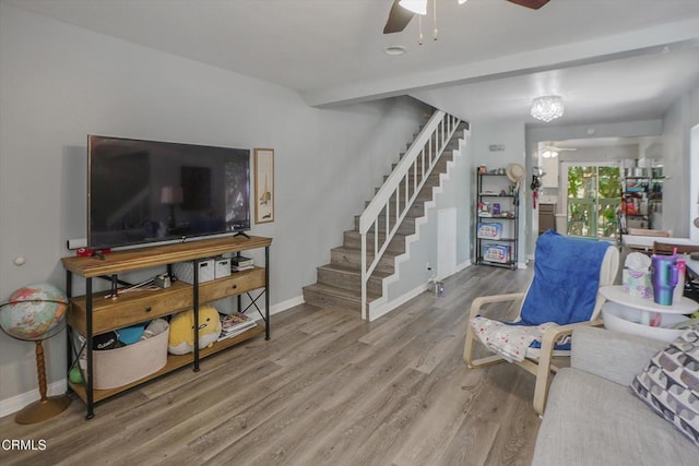 living room featuring ceiling fan, stairway, wood finished floors, and baseboards