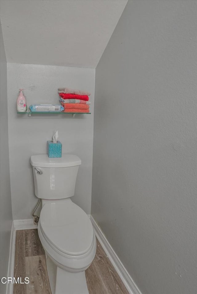 bathroom featuring wood finished floors, baseboards, and toilet