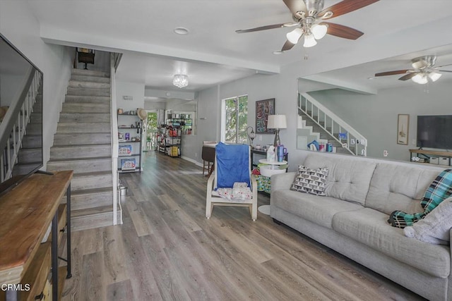 living area with stairs, a ceiling fan, wood finished floors, and baseboards