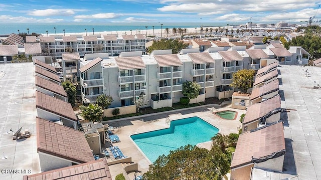 community pool with a water view, a patio area, and a hot tub