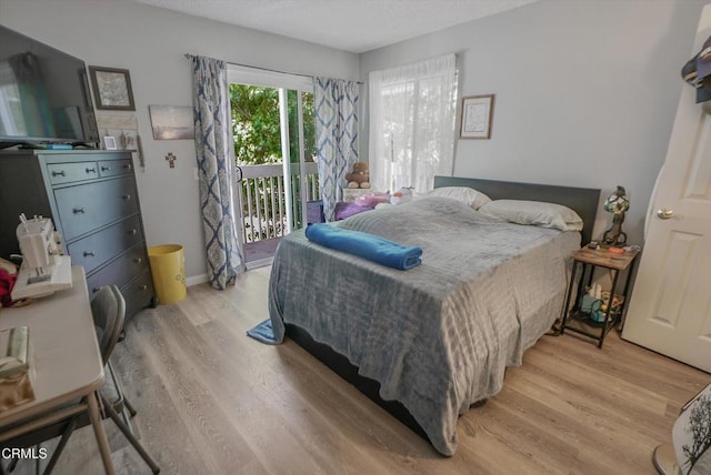 bedroom with access to exterior, light wood finished floors, and baseboards