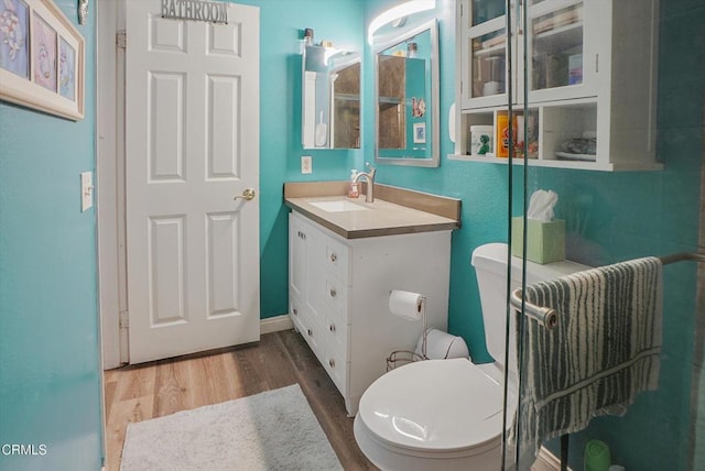 bathroom with toilet, wood finished floors, and vanity