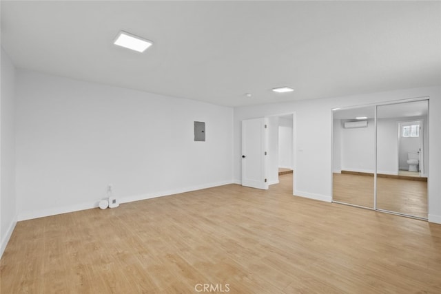 11177 Tamarack Ave, Pacoima, CA 91331 - unfurnished bedroom featuring light wood-style flooring, electric panel, baseboards, and a wall unit AC