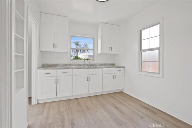 5939 5th Ave, Hyde Park, CA 90043 - kitchen featuring a sink, light wood-style flooring, light countertops, and white cabinets