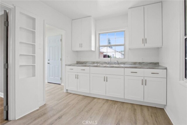 5939 5th Ave, Hyde Park, CA 90043 - kitchen featuring a sink, light wood-style floors, white cabinets, and baseboards