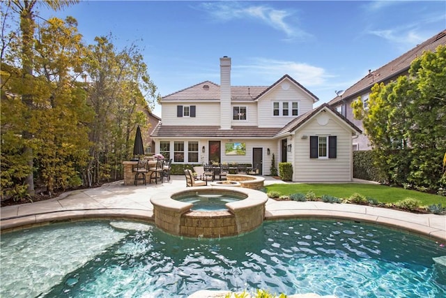 6 Shively Rd, Ladera Ranch, CA 92694 - back of house featuring a chimney, a patio area, a pool with connected hot tub, a lawn, and a tile roof