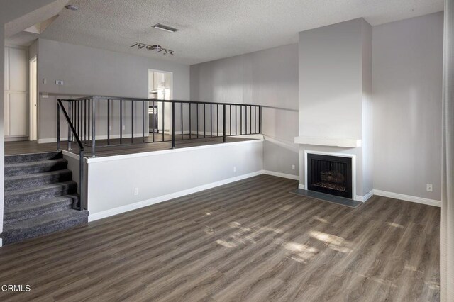 103 E Sierra Madre Blvd Unit E, Sierra Madre, CA 91024 - unfurnished living room featuring wood finished floors, baseboards, a textured ceiling, and a fireplace with flush hearth