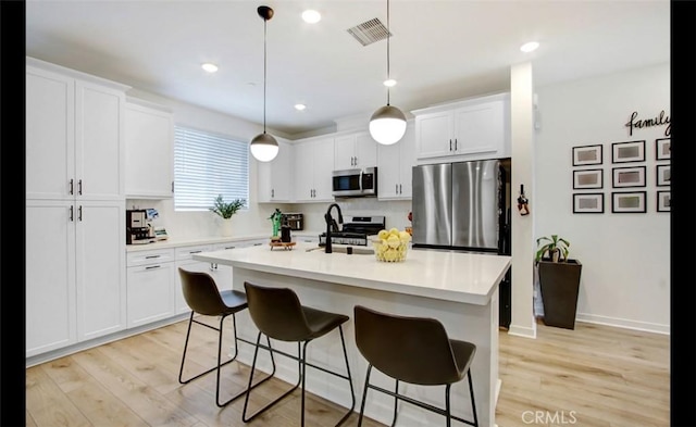 4085 E Liliana Paseo Unit 69, Ontario, CA 91764 - kitchen featuring appliances with stainless steel finishes, light wood-style floors, a kitchen breakfast bar, white cabinets, and recessed lighting