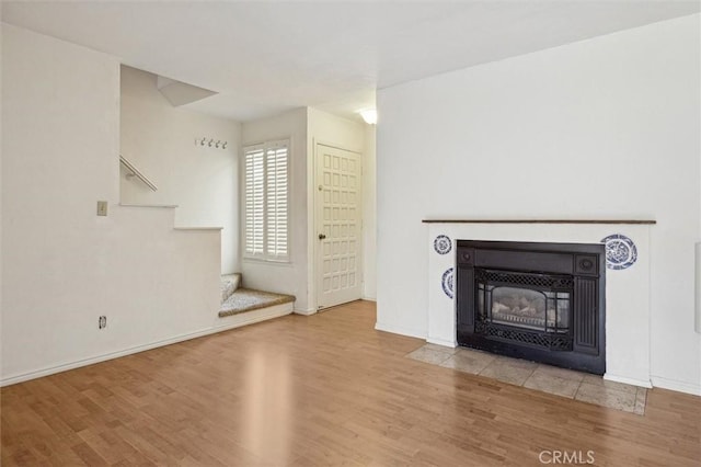 391 Sequoia St Unit 5, Morro Bay, CA 93442 - unfurnished living room featuring wood finished floors, stairs, a fireplace with flush hearth, and baseboards