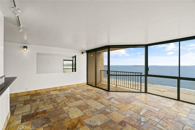 1750 E Ocean Blvd Unit 511, Long Beach, CA 90802 - unfurnished room with stone tile flooring, view of water and beach, baseboards, and expansive windows