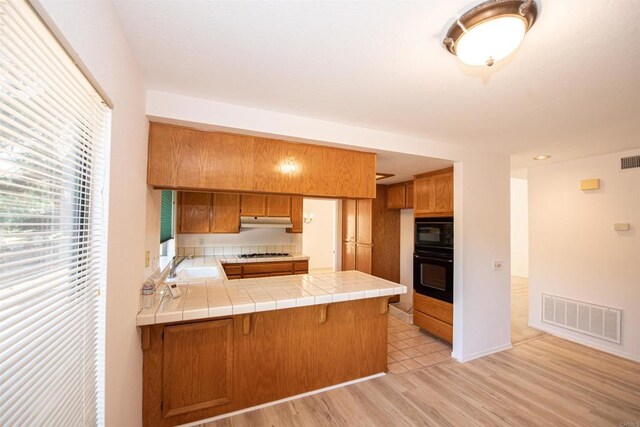 2432 Live Oak Rd, Escondido, CA 92029 - kitchen with black appliances, a sink, under cabinet range hood, a peninsula, and brown cabinetry