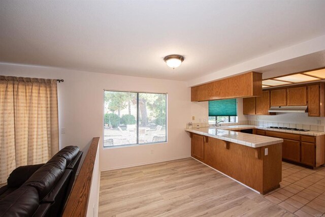 2432 Live Oak Rd, Escondido, CA 92029 - kitchen featuring tile countertops, a peninsula, brown cabinetry, white gas cooktop, and a sink