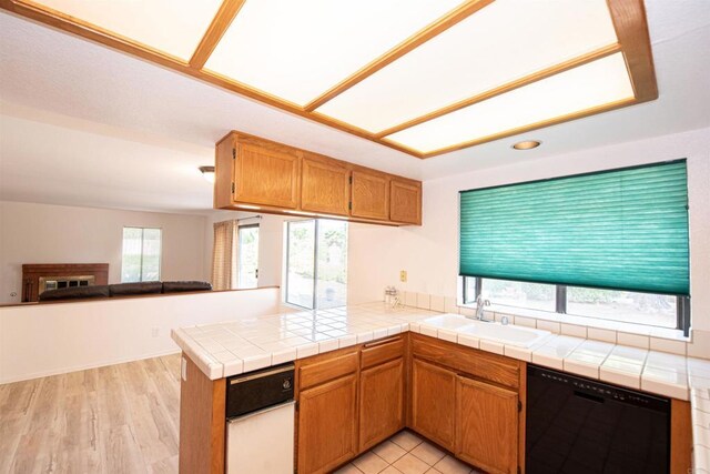 2432 Live Oak Rd, Escondido, CA 92029 - kitchen with black dishwasher, a sink, open floor plan, a peninsula, and brown cabinetry
