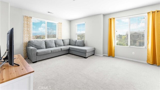 living area featuring light colored carpet and baseboards