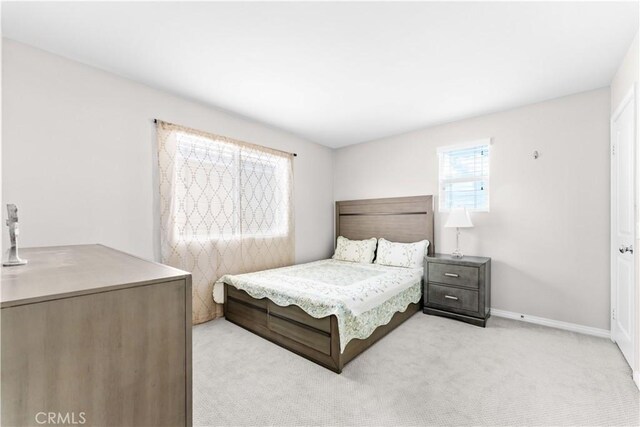 bedroom with light colored carpet and baseboards