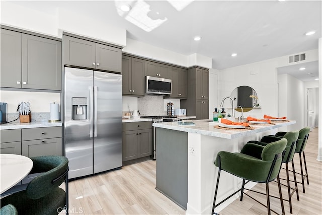 1201 Lasso Way Unit 202, Rancho Mission Viejo, CA 92694 - kitchen with appliances with stainless steel finishes, gray cabinets, light wood finished floors, a sink, and a center island with sink