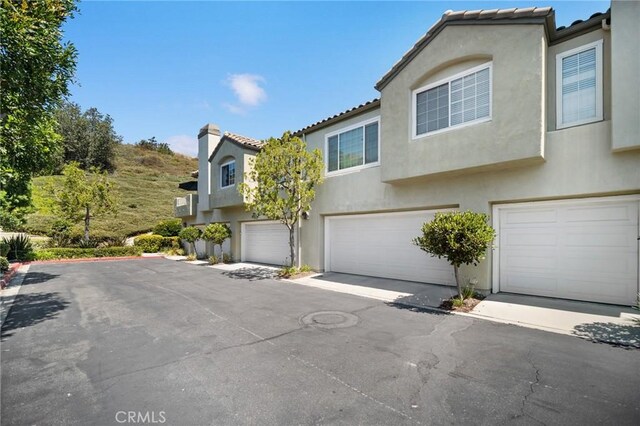 69 Cloudcrest, Aliso Viejo, CA 92656 - view of front facade with stucco siding, a tile roof, and a garage