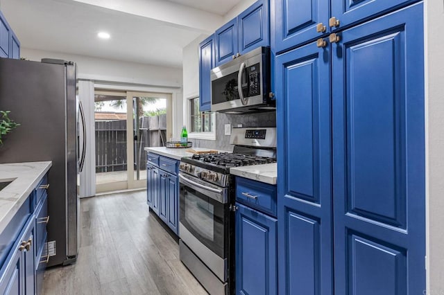 2929 Fire Mountain Dr Unit 9, Oceanside, CA 92054 - kitchen with appliances with stainless steel finishes, blue cabinetry, light wood finished floors, light stone counters, and recessed lighting