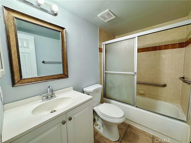 bathroom with tile patterned floors, vanity, shower / bath combination with glass door, toilet, and a textured ceiling