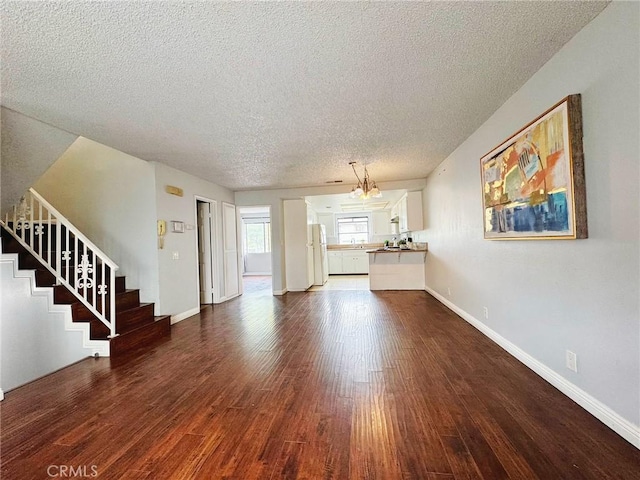 unfurnished living room featuring a textured ceiling, dark wood-style flooring, stairway, and baseboards