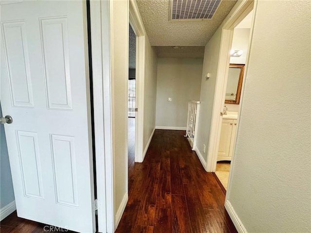 hall featuring hardwood / wood-style floors, baseboards, and a textured ceiling
