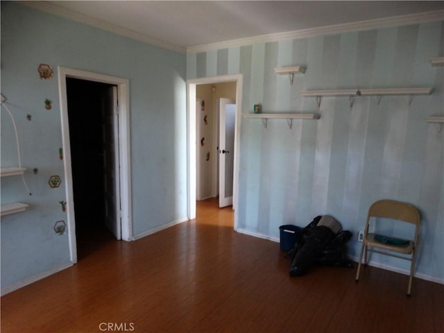 unfurnished room with wood finished floors, ornamental molding, and baseboards