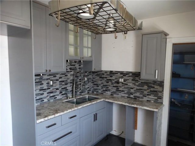 kitchen with a sink, decorative backsplash, and light stone counters