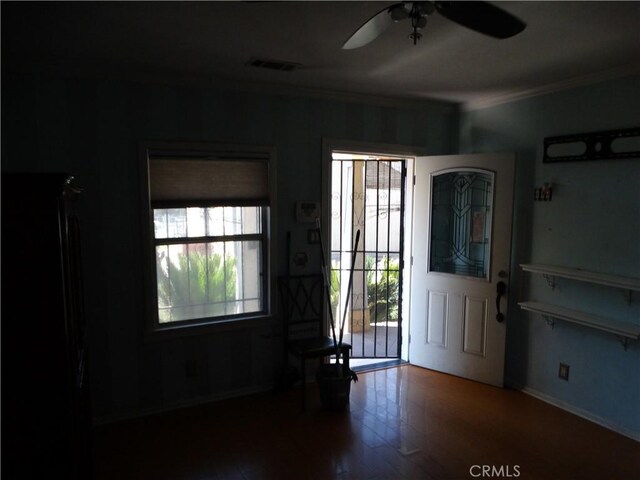 foyer with ornamental molding, ceiling fan, wood finished floors, and baseboards
