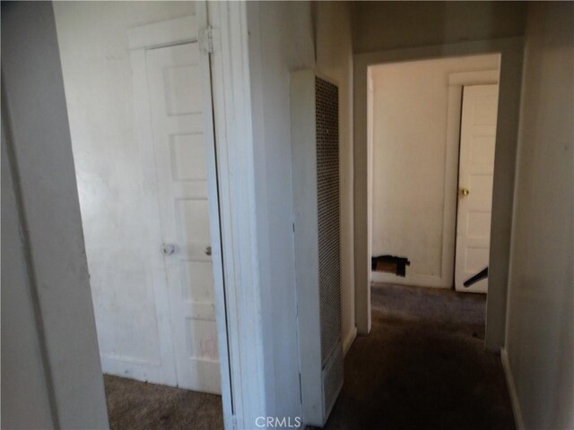 hallway featuring a heating unit and dark carpet