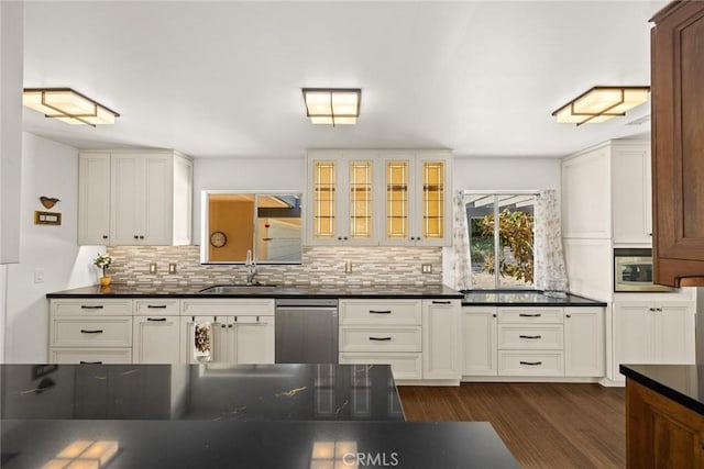 kitchen with stainless steel appliances, dark countertops, a sink, and tasteful backsplash
