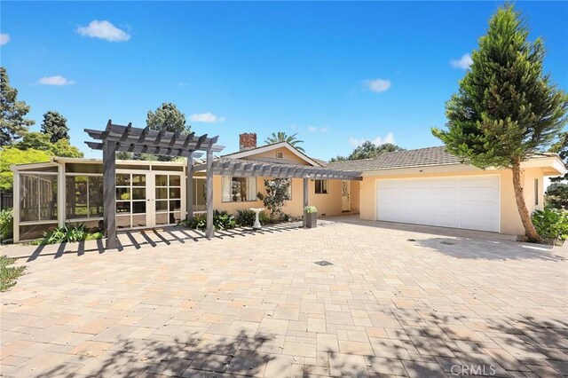 view of front of house featuring a pergola, an attached garage, driveway, and stucco siding