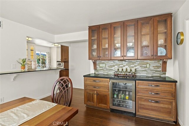 indoor dry bar with beverage cooler, backsplash, and dark wood-type flooring