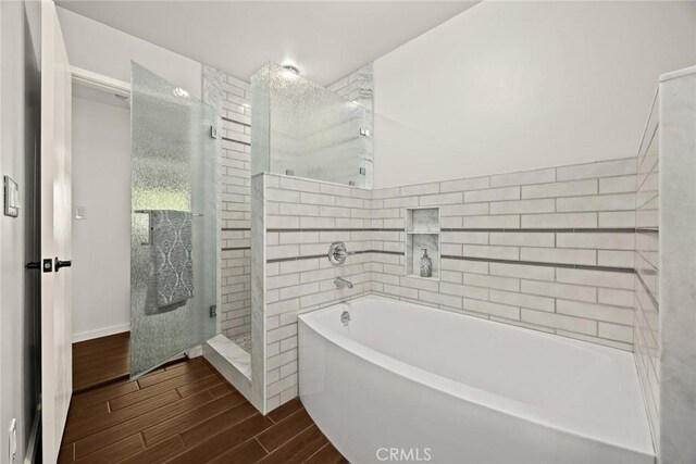 full bathroom with wood finished floors, tiled shower, and a bath