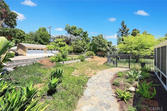 view of yard featuring fence, a garage, and a garden
