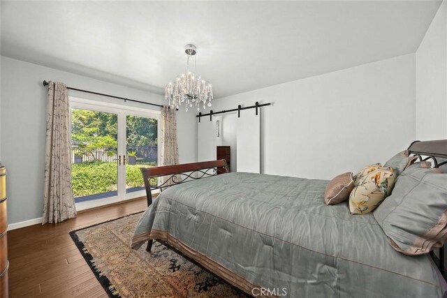bedroom with wood finished floors, a barn door, baseboards, access to outside, and a chandelier