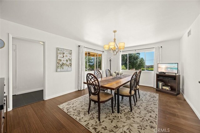 dining area featuring a chandelier, dark wood-type flooring, and baseboards