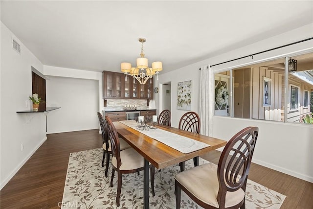 dining area with a chandelier, dark wood-style floors, and baseboards
