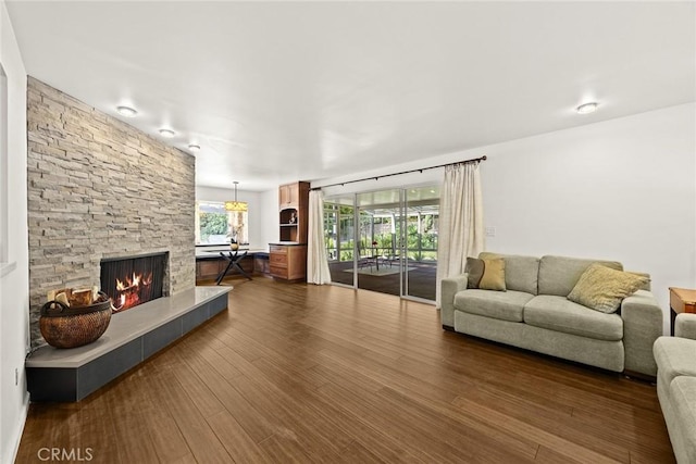 living room with a stone fireplace and dark wood-style floors