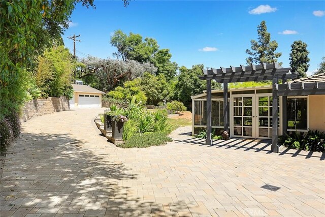 view of patio featuring a pergola, a detached garage, and an outbuilding