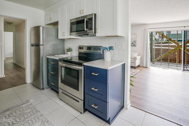 kitchen featuring stainless steel appliances, white cabinets, light countertops, and backsplash