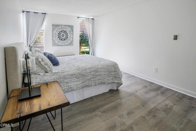 bedroom with wood finished floors, baseboards, and a textured ceiling