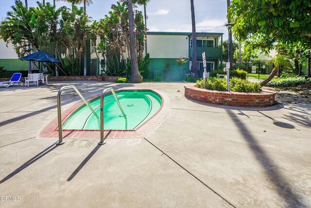view of swimming pool featuring a community hot tub, a patio area, and fence