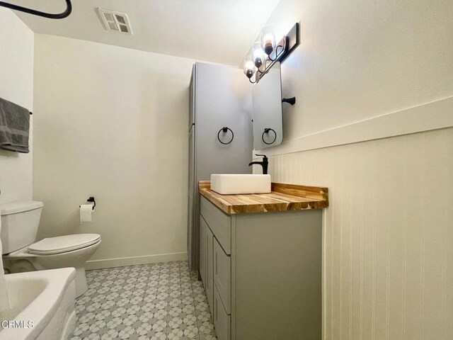 bathroom featuring tile patterned floors, toilet, vanity, and a tub to relax in
