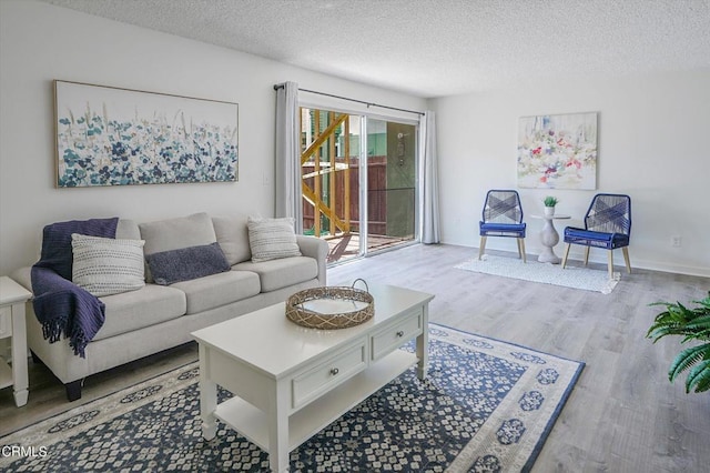 living room featuring a textured ceiling, wood finished floors, and baseboards